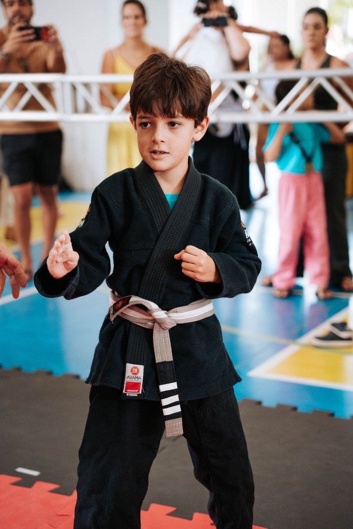 Henrique de kimono preto, em posição de guarda, no tatame